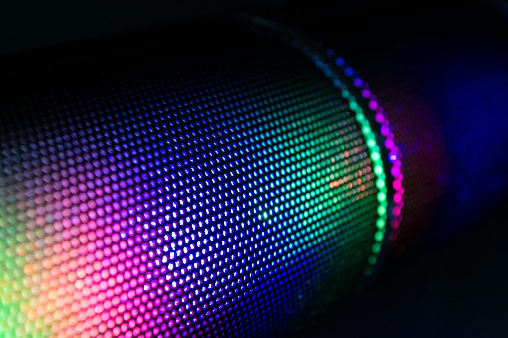 Close-up of a wireless speaker with colorful RGB lighting illuminating the mesh surface.