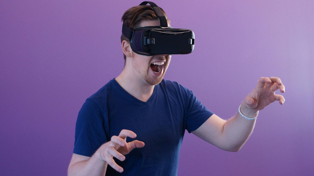 Young man expresses excitement while using a virtual reality headset in a modern setting.