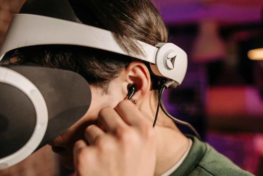 Close-up of a person wearing virtual reality headset and earphones indoors.